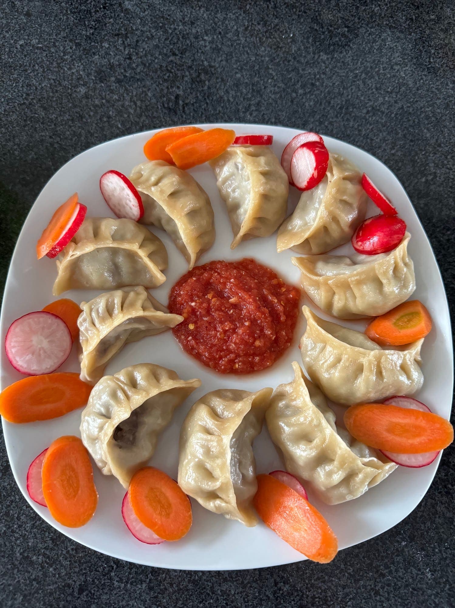 Steamed momo with Tibetan chutney, carrots and radishes